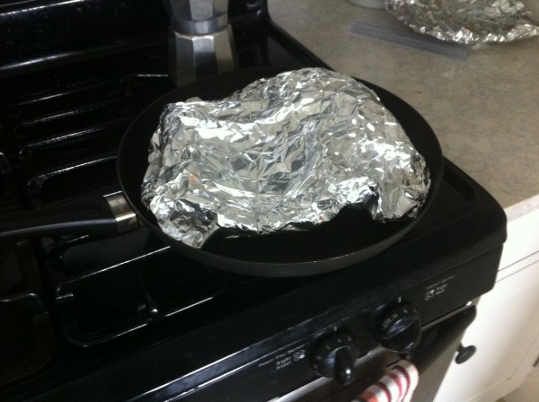 Beneath the loose dome of foil is a slice of pizza. 